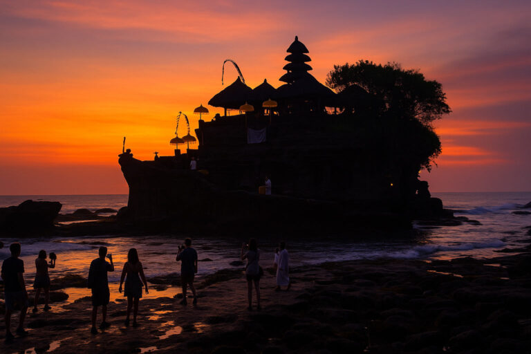 Private driver watching sunset while guests visit Tanah Lot Temple.