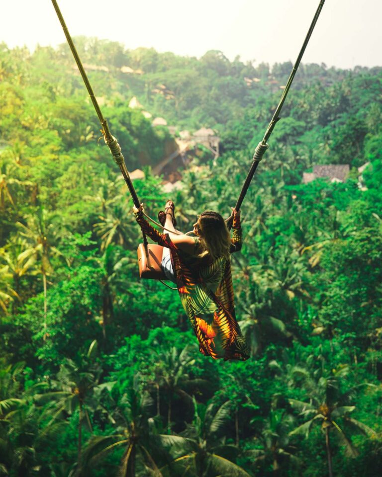 Woman swinging over Ubud jungle rice fields
