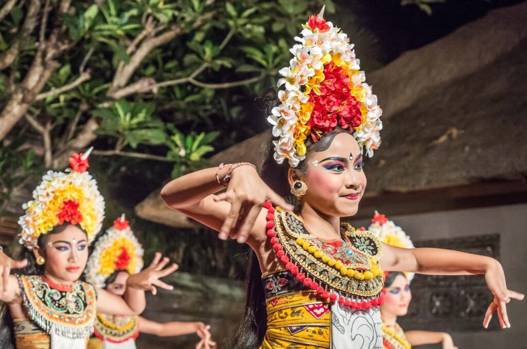 oung Balinese dancer performing Baris dance for tourists in a temple setting.